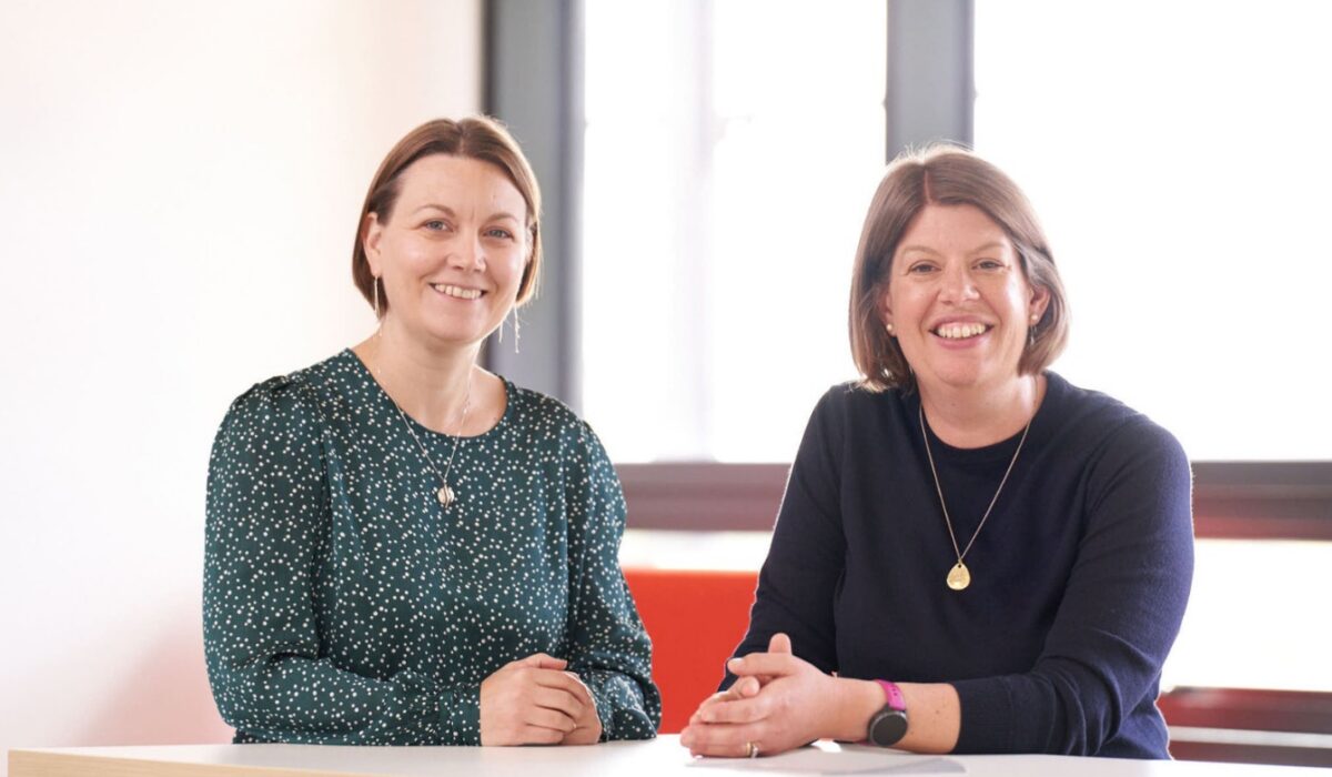 Davinia and Carol sat at a desk, smiling to camera.